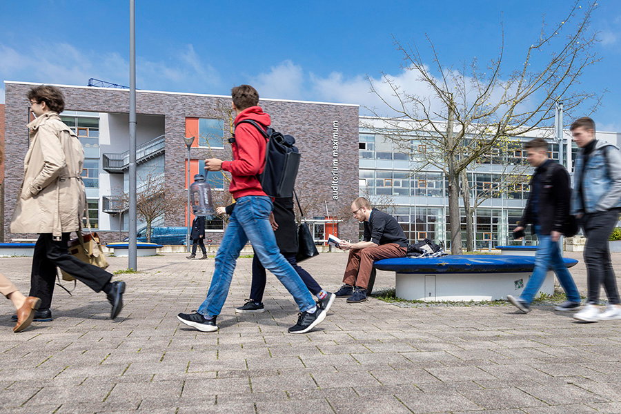 Studierende laufen über den Campusplatz der dem Auditorium Maximum