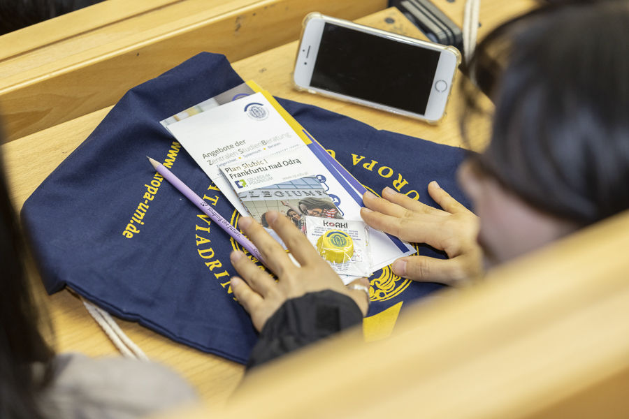 Flyer, Viadrina-Beutel und andere Utensilien liegen auf einem Hörsaaltisch